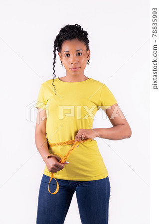 Happy looking afro american woman measuring her waist Happy looking afro american woman measuring her waist 78835993