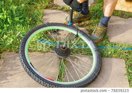 Bike mechanic man repairs bicycle in bicycle repair shop, outdoor. Hand of cyclist bicyclist examines, fixes modern cycle transmission system. Bike maintenance, sport shop concept. 78839223