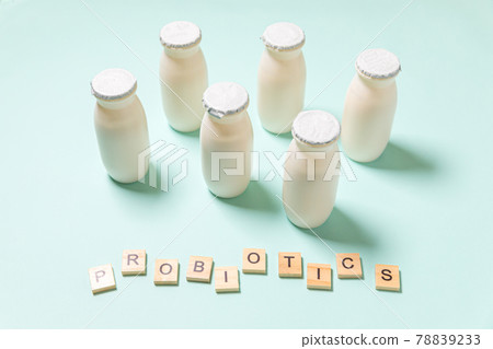 Small bottles with probiotics and prebiotics dairy drink on blue background. Production with biologically active additives. Fermentation and diet healthy food. Bio yogurt with useful microorganisms. 78839233