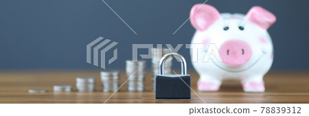 Padlock standing on background of piggy bank and coins closeup 78839312