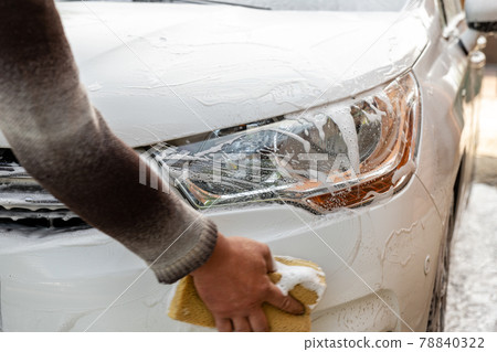 Close-up detail manual car wash with high pressure water equipment pump and soapy sponge at home backyard outdoor summer day. Vehicle covered by foam shampoo chemical detergents carwash self service Close-up detail manual car wash with high pressure water equipment pump and soapy sponge at home backyard outdoor summer day. Vehicle covered by foam shampoo chemical detergents carwash self service 78840322