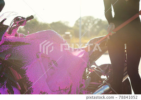 Close up high pressure pink foam washes a motorcycle at self-service car wash. Selective focus. 78841052