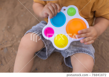 colorful trendy antistress sensory toy fidget push pop it and simple dimple in kid's hands, children share toys and playing together. 78841872