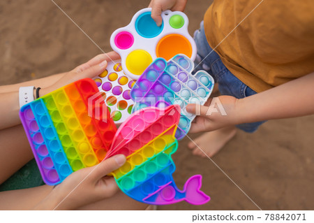 Colorful antistress sensory toy fidget push pop it in toddler's hands. Antistress trendy pop it toy. Rainbow sensory fidget. New trendy silicone toy. dolphin shape Colorful antistress sensory toy fidget push pop it in toddler's hands. Antistress trendy pop it toy. Rainbow sensory fidget. New trendy silicone toy. dolphin shape 78842071