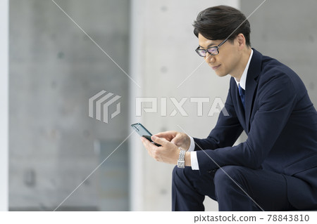 Businessman looking at the screen of a smartphone Businessman looking at the screen of a smartphone 78843810
