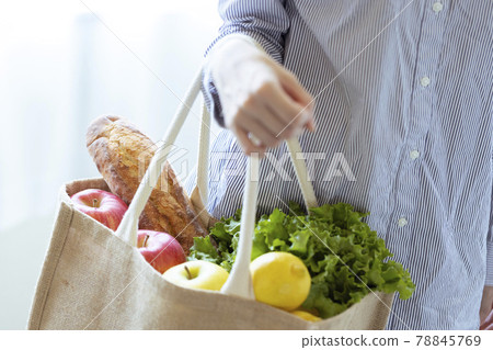 A woman holding vegetables and bread in an eco bag A woman holding vegetables and bread in an eco bag 78845769