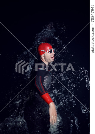 triathlon athlete swimming in dark night wearing wetsuit 78847943