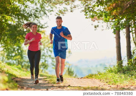 couple enjoying in a healthy lifestyle while jogging on a country road couple enjoying in a healthy lifestyle while jogging on a country road 78848380