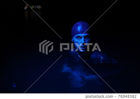 authentic triathlete swimmer having a break during hard training on night neon gel light 78848382