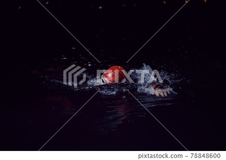 triathlon athlete swimming in dark night wearing wetsuit 78848600