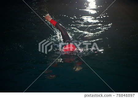 triathlon athlete swimming in dark night wearing wetsuit triathlon athlete swimming in dark night wearing wetsuit 78848897