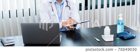 Medical concept a male doctor wearing a mask writing prescription to patient at his modern clinic for recovering from Coronavirus (COVID-19) 78849030