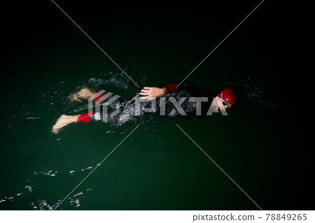 triathlon athlete swimming in dark night wearing wetsuit 78849265