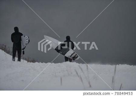 Arctic surfers running on beach after surfing 78849453