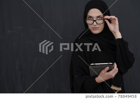 Young Arab businesswoman in traditional clothes or abaya holding tablet computer 78849458