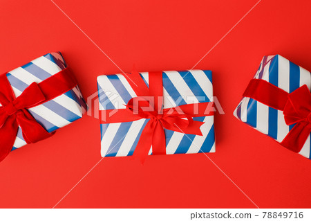 Blue and white stripe gift boxes with red bows on classic red background in the national colors of America, Russia, France or England, the concept of Independence Day, a national holiday, sale Blue and white stripe gift boxes with red bows on classic red background in the national colors of America, Russia, France or England, the concept of Independence Day, a national holiday, sale 78849716