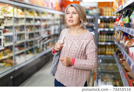 Thoughtful mature woman among shelves in grocery shop Thoughtful mature woman among shelves in grocery shop 78850538