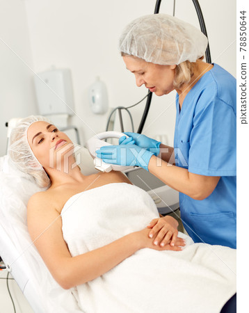 Doctor removes hair from face of woman with laser in a cosmetology clinic Doctor removes hair from face of woman with laser in a cosmetology clinic 78850644