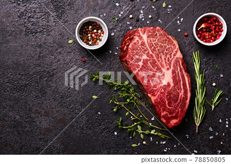 Fresh raw marbled beef rib eye steak and spices on black stone background, copy space 78850805