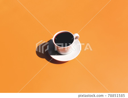 Cup and plate of coffee with shadow of sun on yellow terracotta background Cup and plate of coffee with shadow of sun on yellow terracotta background 78851585