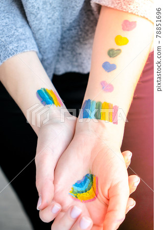 Rainbow LGBTQ flag painted on hand. Support for lgbt community. Honour of pride month. Connecting people, touching hands. Selective focus 78851696