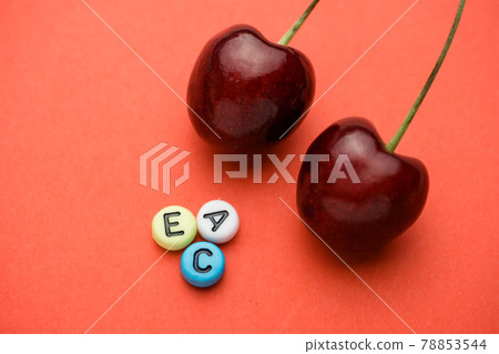 Close up of letters indicating the vitamins contained in cherries near the two berries. 78853544