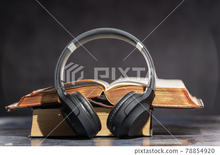 Headphones lying next to old books. Audiobook Concept Headphones lying next to old books. Audiobook Concept 78854920