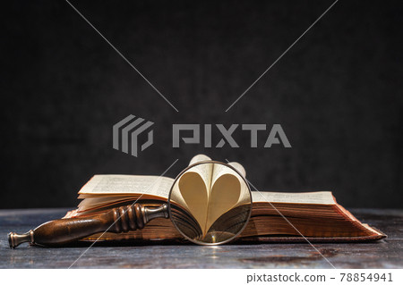 Opened old book with hart shaped from two pages 78854941