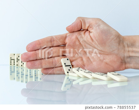 Hand stopping domino effect on white background. 78855537