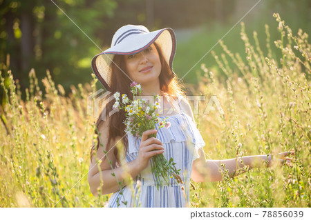 Young woman picking flowers in the meadow in summer evening 78856039