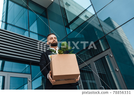 Fired depressed male office worker with box of personal stuff walking outdoor, lost job and left without money 78856331
