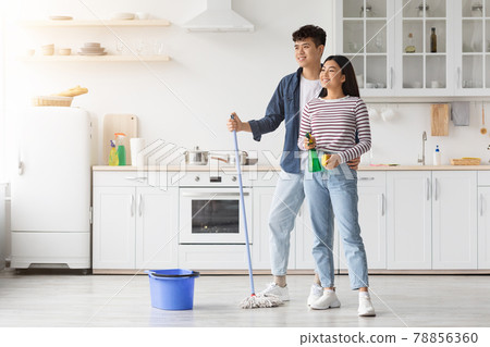 Young asian couple mopping floor in kitchen Young asian couple mopping floor in kitchen 78856360