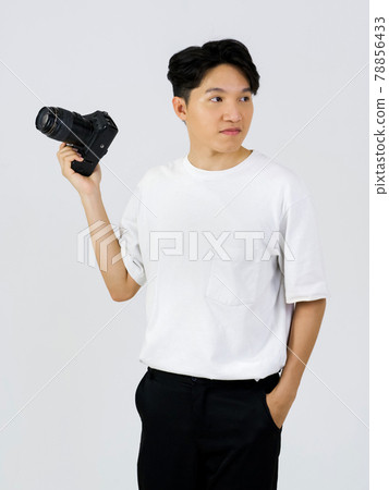 Asian photographer looking outside while standing in a white photography scene. The atmosphere in the photo studio. 78856433