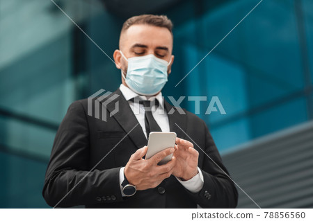 Mature businessman wearing face mask and using smartphone, going home after work day in office. Coronavirus protection 78856560
