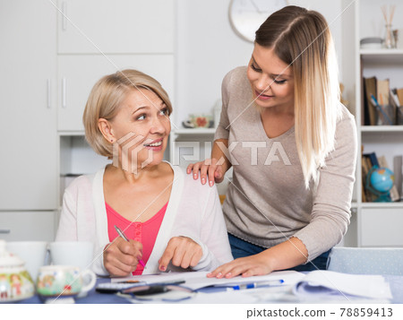 Daughter helps mother to lead home accounting Daughter helps mother to lead home accounting 78859413