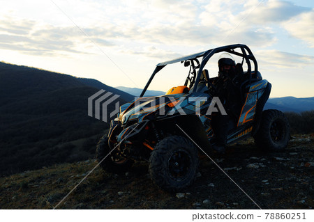 Man in helmet sitting on ATV quad bike in mountains 78860251