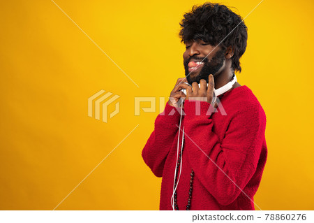 Young african american man with white headphones against yellow background 78860276
