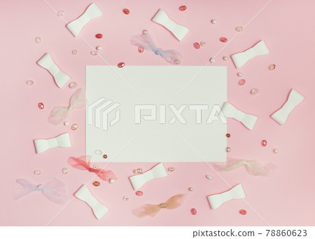 Sheet of paper on Pink paper background with ribbons and beads. 78860623