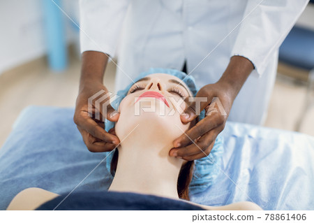 Beautiful woman, lying on the couch, enjoying facial massage with closed eyes 78861406