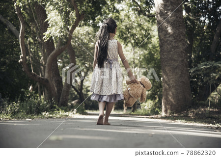 Sad girl hugging teddy bear sadness alone in green garden park. Lonely girl feeling sad unhappy walking outdoors with best friend toy. Autism child play teddy bear best friend. Family violence concept 78862320