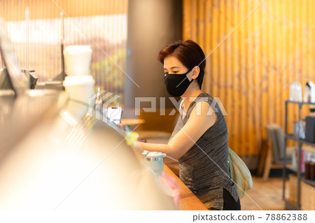 Woman customer with protective mask paying bill by cell phone in cafe. 78862388
