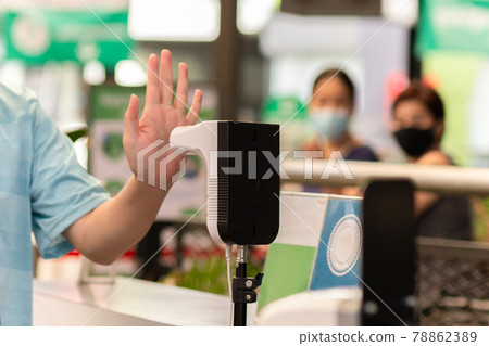 Man checking body temperature by infrared digital thermometer with his hand. 78862389