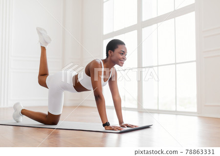 Happy Black Woman In White Sportswear Doing Donkey Kicks Exercise 78863331
