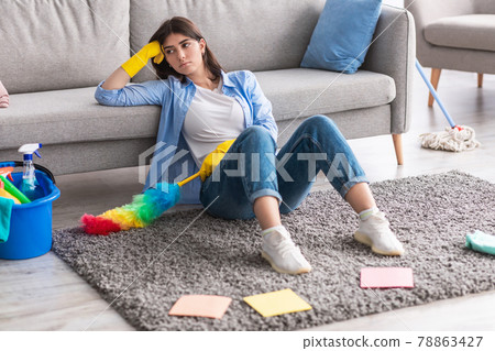 Upset woman tired of cleaning sitting on floor carpet Upset woman tired of cleaning sitting on floor carpet 78863427