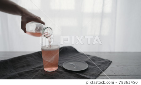 Man pour pink sparkling drink into tumbler glass with ice chunk Man pour pink sparkling drink into tumbler glass with ice chunk 78863450