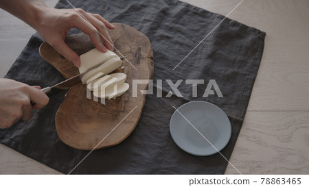 Man slicing mozzarella on olive wood board for sandwich Man slicing mozzarella on olive wood board for sandwich 78863465