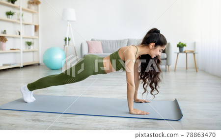 Side view of millennial Indian woman standing in plank pose on yoga mat at home, panorama 78863470