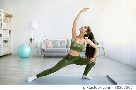 Flexibility exercises for healthy living. Fit Indian woman stretching her body during home workout, copy space Flexibility exercises for healthy living. Fit Indian woman stretching her body during home workout, copy space 78863505