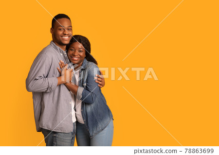 Portrait Of Affectionate African American Couple Embracing While Posing Over Yellow Background 78863699