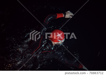triathlon athlete swimming in dark night wearing wetsuit 78863712